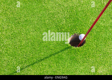 Mini-Golf-Ball in das Loch geht in Nahaufnahme Stockfoto