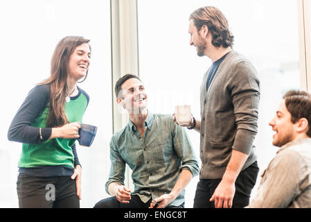 Vier arbeiten Kolleginnen und Kollegen auf eine Pause, gemeinsam lachen. Stockfoto