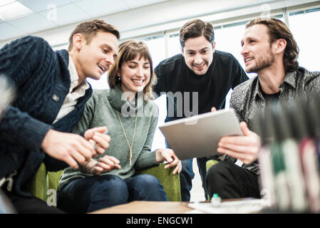 Vier Menschen, Kollegen bei einem Treffen und ein Mann, einen Tablet mit der Gruppe teilen. Stockfoto