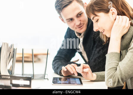 Ein Mann und eine Frau sitzen nebeneinander an einem Schreibtisch in einem Büro zu sprechen. Stockfoto