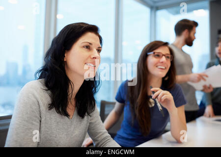 Zwei Unternehmerinnen, Frauen sitzen an einem Schreibtisch sprechen angeregt. Stockfoto