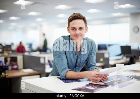 Ein Mann lächelte und beugte sich auf seinem Schreibtisch. Stockfoto