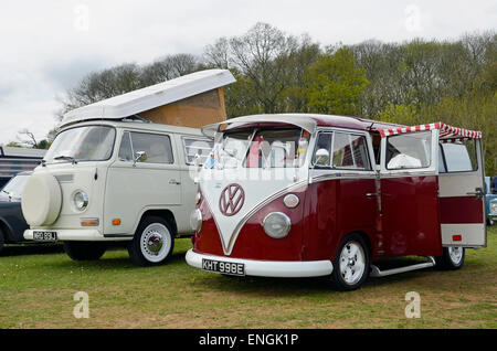 Volkswagen Wohnmobile aus zwei verschiedenen Epochen - eine geteilte Windschutzscheibe aus den 1950er Jahren und ein Erker aus den späten 1960er Jahren. Stockfoto