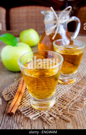 Apfeltee (Apfelwein) mit Zimt sticks, grüne Äpfel und Blätter auf rustikalen hölzernen Hintergrund Stockfoto