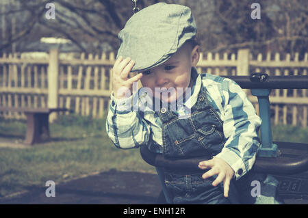 Getönten Vintage-Style Portrait Kleinkind in Latzhosen und Flatcap in einem Schwung Stockfoto