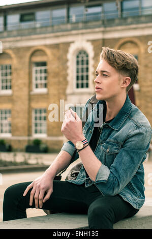 Kaukasischen Jüngling in Denim Jacke Rauchen an einer Wand in London Stockfoto