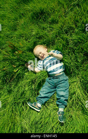 Süße männliche Kleinkind in einem blau-weißen stripey T-shirt in einem sonnigen Bereich spielen Stockfoto