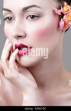 Natürliche Schönheit Kopfschuss der blasse junge Frau mit roten und rosa Lippenstift und Blumen im Haar Stockfoto