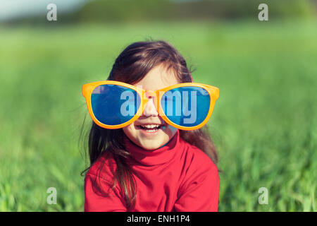 Glücklich lächelnde Mädchen mit großen Sonnenbrille auf dem Feld Stockfoto