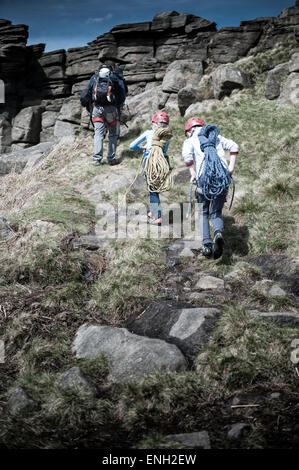 Ein kleiner Junge und ein Mädchen auf einer Kletter-Expedition folgen ihrem Lehrer auf einem Pfad Stockfoto