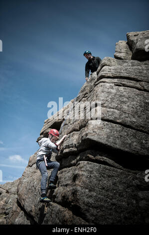 Ein kleiner Junge, Klettern auf Stanage Edge im Peak District Stockfoto