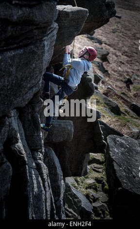 Ein kleiner Junge, Klettern auf Stanage Edge im Peak District Stockfoto