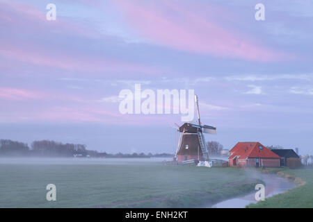 alte Windmühle in Nebel Sonnenaufgang Fluss, Niederlande Stockfoto