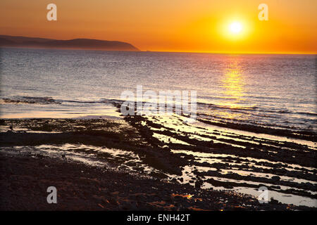 Sonnenuntergang am Strand von Kilve in West Somerset mit blauen, gelben und braunen Lias mit Fossilien eingebettet Stockfoto