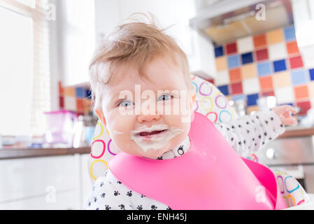 Sechs Monate altes Babymädchen mit chaotisch Gesicht nach der Fütterung auf Brei Stockfoto