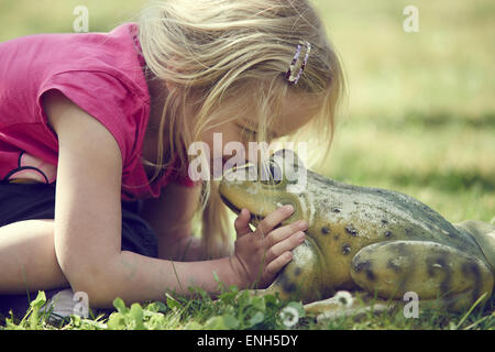 Kleines blondes Mädchen küssen verzaubert Froschkönig Stockfoto