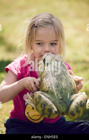 Kleines blondes Mädchen küssen verzaubert Froschkönig Stockfoto