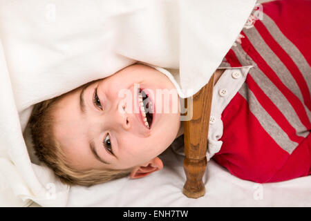 Sechs Jahre alten Jungen haben Spaß beim spielen und versteckt unter einem gedeckten Tisch Stockfoto