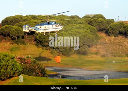 Kamov Ka-32A11BC Hubschrauber (Registrierung EG-JSQ) sammeln Wasser zur Brandbekämpfung von einem Golfplatz See Cabopino Golf. Stockfoto