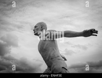 Weiße steinerne Statue eines Mannes laufen in den Wolken in monochrom schwarz / weiß Stockfoto