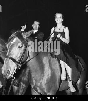 Britischer Musiker Ronnie Ronalde und Braut Corsie auf dem Pferderücken, Teilnahme an einem Rennen um Berkeley Square im Rahmen einer Weihnachtsfeier von Mayfair Club für ein Kinderhilfswerk organisiert. 21. Dezember 1956. Stockfoto