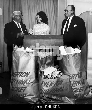 Welt Cup Queen 1966. Sheila Forrest macht ein Unentschieden für die Balance der Everton-Aktie von Tickets für den FA-Cup-Finale V West Brom im Wembley-Stadion zu entsprechen. Beobachten sind Jack Sharp (links), der Everton-Vorsitzende und George Watts ein Direktor des Clubs. Auslosung am t Stockfoto