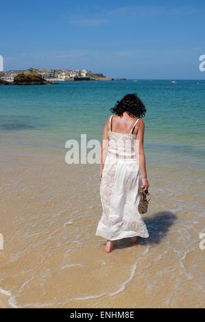 St Ives, Cornwall: Frau im Sommerkleid zu Fuß entlang des Wassers auf Porthminster Beach in St Ives auf der Cornwall Stockfoto