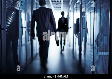 Silhouetten von Geschäftsleuten zu Fuß entlang des Bürogebäudes Stockfoto