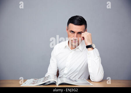 Ernst Kaufmann am Tisch sitzen und Blick in die Kamera über den grauen Hintergrund Stockfoto