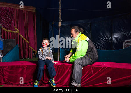 Verkleidet als Clown mit Make und gestreiftes Hemd sitzt auf der Bühne mit Mann Lachen Boy Stockfoto