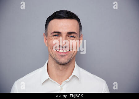 Porträt eines glücklichen jungen Geschäftsmann Blick in die Kamera über den grauen Hintergrund Stockfoto