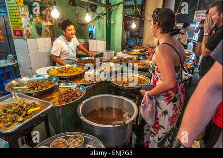 Eine weibliche Touristen Bestellung eine Auswahl an thailändischen Speisen an einem Stand an der Tha Chang Pier Bootsmarkt. Bangkok. Thailand Stockfoto