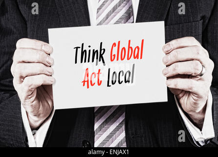 Ein Geschäftsmann hielt eine Karte mit den Worten: Think Global Act Local, darauf geschrieben. Stockfoto