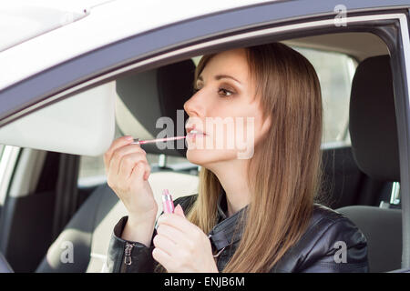 Junge hübsche Frau Schminken im Auto. Geschäftsfrau mit Lippenstift im Automobil Stockfoto