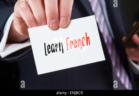Ein Geschäftsmann hält eine Visitenkarte mit den Worten, Französisch lernen, darauf geschrieben. Stockfoto