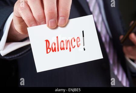 Ein Geschäftsmann hält eine Visitenkarte mit den Worten: Balance, darauf geschrieben. Stockfoto