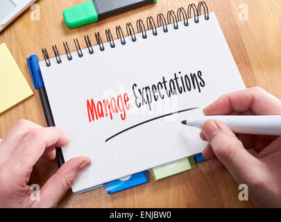 Ein Geschäftsmann, der Wörter verwalten Erwartungen auf einen Notizblock zu schreiben. Stockfoto