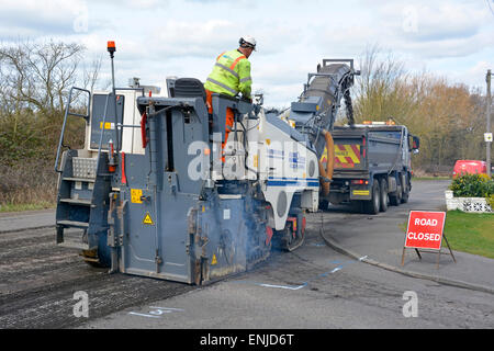 Defekte, abgenutzte Asphaltstraße wird abgefräst, um die Aufarbeitung von Kipper-Lkw-Ladeabfällen für das Recycling von Brentwood Essex England vorzubereiten Stockfoto