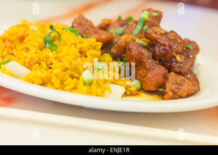 Scharf und würzig General Tso Huhn serviert mit einer Seitenlänge von Schweinefleisch gebraten Reis Stockfoto