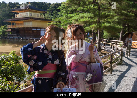 Zwei Japaner Mädchen posiert in Kinkaku-Ji, Tempel des goldenen Pavillons, Kyoto salutieren, Stockfoto