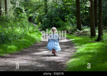 Kleines Mädchen im blauen Kleid, die durch den Wald laufen. Stockfoto