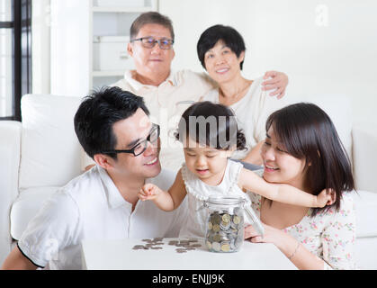 Kleinkind Münzen zählen. Asiatische Familie Geld sparen Konzept. Multi-Generationen Lebensweise zu Hause. Stockfoto