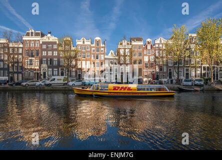 Amsterdam Singel Gracht mit DHL Lieferung Kanalboot im frühen Morgen um 07:00 im Frühjahr. Stockfoto