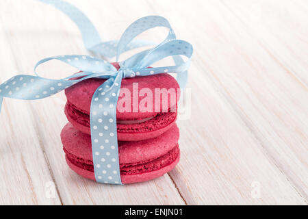 Roten Macarons mit blauem Band auf weißer Holztisch Stockfoto