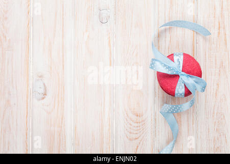 Roten Macarons mit blauem Band auf weißer Holztisch mit Textfreiraum. Ansicht von oben Stockfoto
