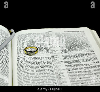 Einzelne Diamant Ehering auf Bibel offen für Ehe auf schwarzen Hintergrund Stockfoto