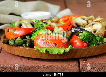 Gegrilltes Gemüse (Paprika, Spargel, Pilze, Brokkoli) in einer hölzernen Platte Stockfoto