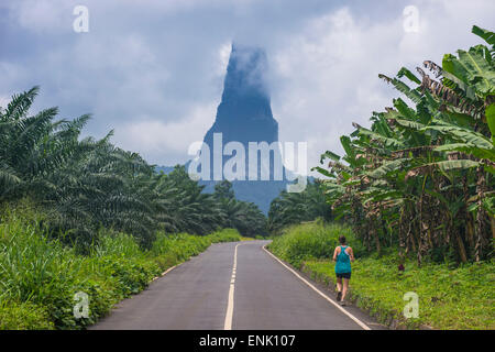 Läufer auf eine Straße nach der ungewöhnlichen Monolith, Pico Cao Grande, Ostküste von São Tomé, Sao Tome und Principe, Atlantik Stockfoto