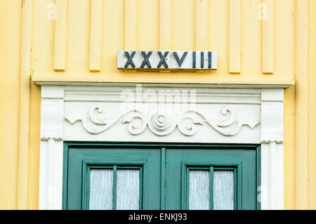 Römische Zahl 39 XXXVIII (hätte XXXIX wenn du es richtig) über eine grüne Tür auf einem gelben und weißen Gebäude. Stockfoto
