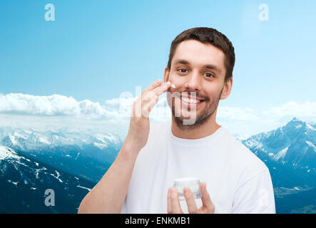 schöne lächelnder Mann applyin Creme Stockfoto